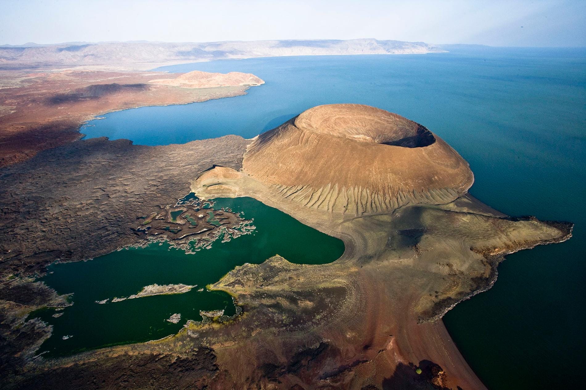 Aerial view of a volcanic crater beside a deep blue rift lake